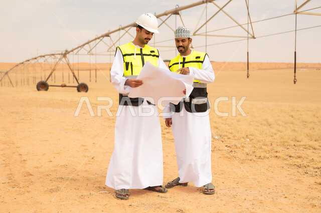 مهندسون عمانيون يراجعون مخططات هندسية في الصحراء
