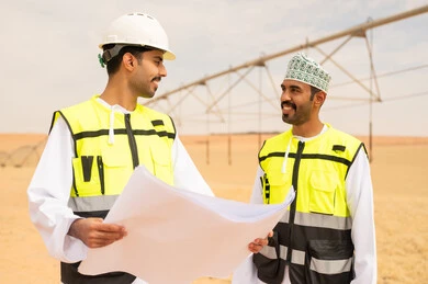 مهندسون عمانيون يناقشون مخططاً هندسياً في مزرعة