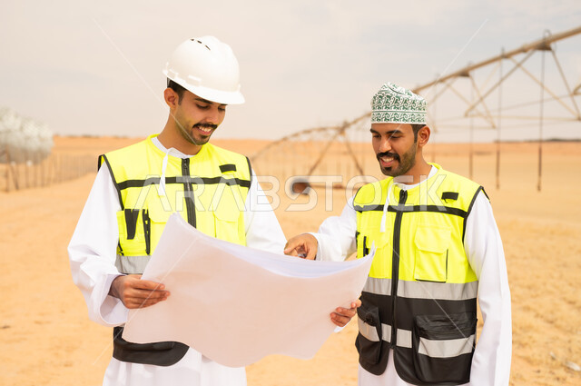 مهندسون عمانيون يراجعون مخططاً في مزرعة صحراوية
