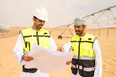 مهندسون عمانيون يراجعون مخططاً في مزرعة صحراوية