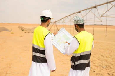مهندسون عمانيون يراجعون مخططات في مزرعة صحراوية