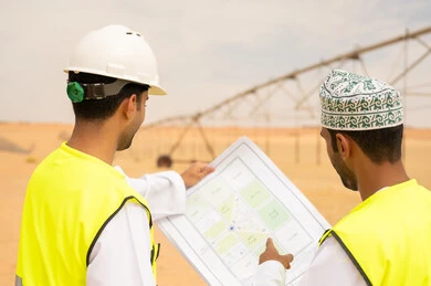 مهندسون عمانيون يراجعون مخططات في موقع صحراوي