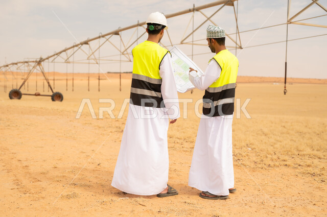 مهندسان عمانيان يراجعان المخططات في مزرعة صحراوية