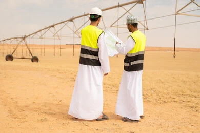 مهندسان عمانيان يراجعان المخططات في مزرعة صحراوية