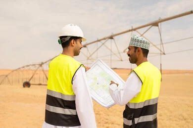 مهندسون عمانيون يراجعون مخططات في مزرعة صحراوية