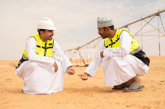 مهندسان زراعيان عُمانيان يتفحصان التربة في الصحراء