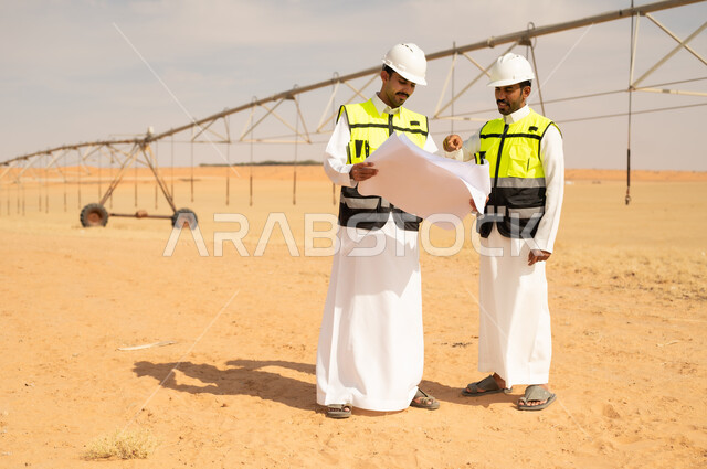 مهندسون سعوديون يراجعون مخططات مشروع ري زراعي صحراوي