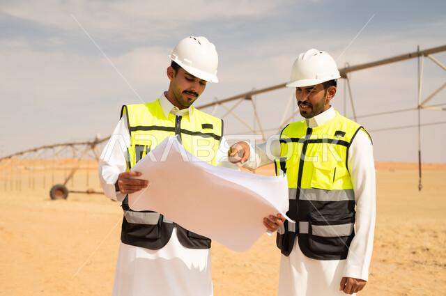 مهندسون سعوديون يراجعون مخططات في حقل زراعي