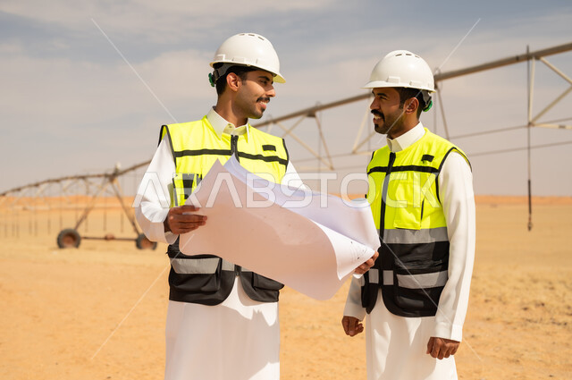 مهندسون سعوديون مع مخططات في موقع عمل صحراوي