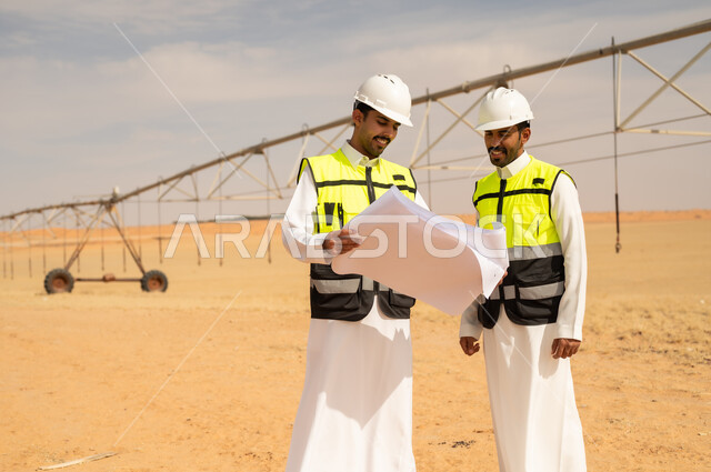 مهندسون سعوديون يراجعون المخططات في موقع ري صحراوي