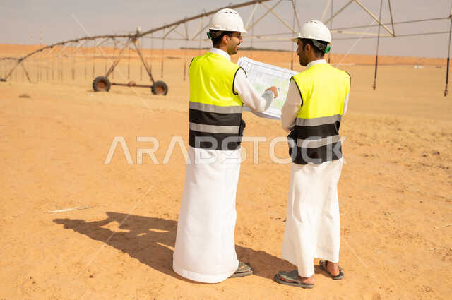 Saudi Engineers Discussing Blueprints in Desert Project