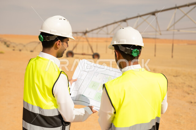 مهندسون سعوديون يراجعون مخططات في موقع ري صحراوي