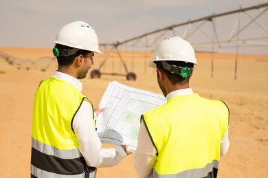 مهندسون سعوديون يراجعون مخططات في موقع ري صحراوي