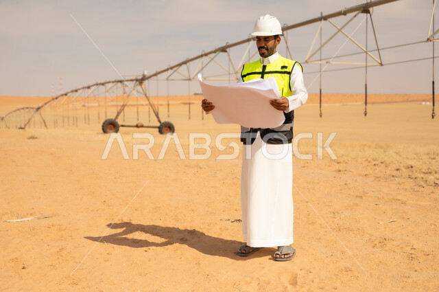 مهندس سعودي مع مخططات في موقع ري زراعي
