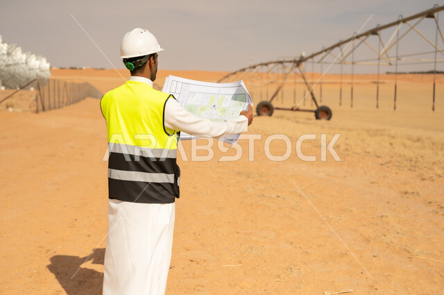 مهندس سعودي يحمل مخطط في مزرعة صحراوية
