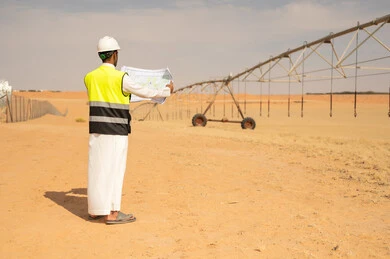 مهندس عربي يحمل مخططاً في مزرعة ري صحراوية