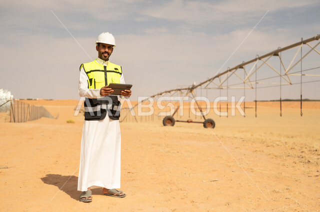 مهندس سعودي مع جهاز لوحي في مزرعة صحراوية