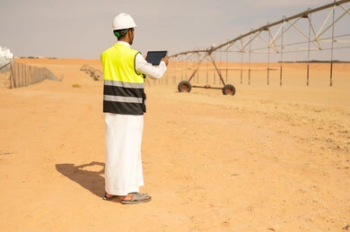 مهندس زراعي سعودي مع جهاز لوحي في مزرعة صحراوية