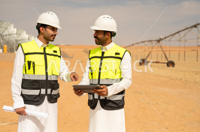 مهندسون سعوديون في موقع زراعي صحراوي مع جهاز لوحي