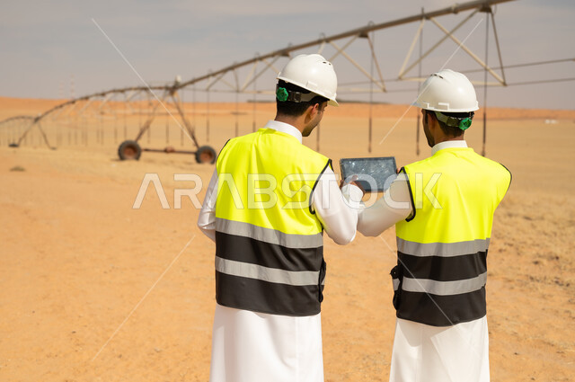 مهندسون سعوديون مع جهاز لوحي في موقع ري صحراوي