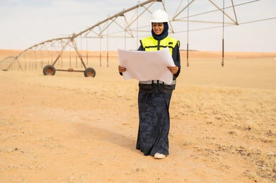 مهندسة سعودية تراجع المخططات في مزرعة صحراوية