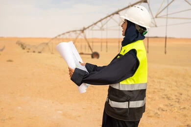 Saudi Female Engineer with Blueprints at Desert Farm