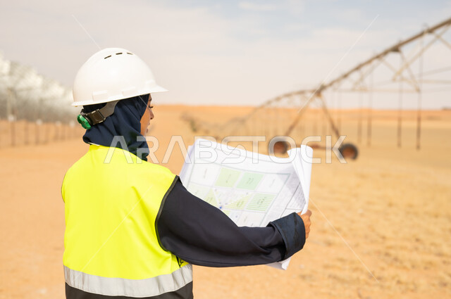 مهندسة عربية مع مخططات في مزرعة صحراوية