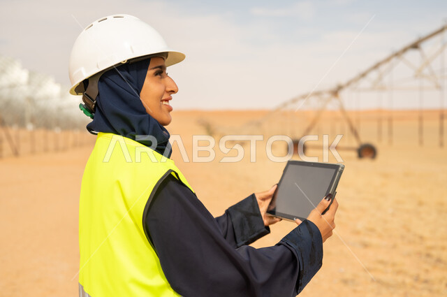 مهندسة سعودية مع جهاز لوحي في مزرعة صحراوية
