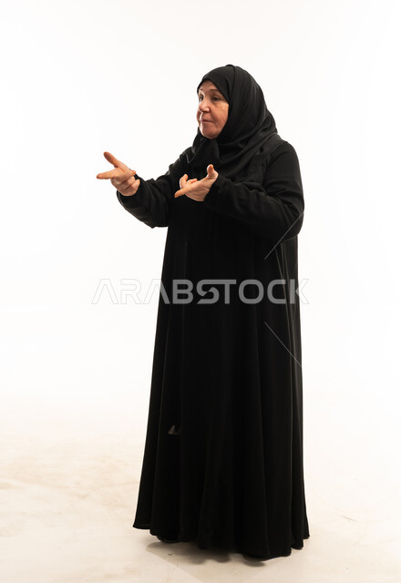 امرأة سعودية مسنة بالعباءة السوداء مع إيماءات اليد