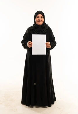 امرأة عربية مسنة تمسك ورقة بيضاء في الاستوديو