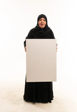 امرأة سعودية مسنة تمسك لوحة بيضاء فارغة في الاستوديو
