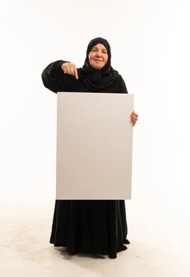 امرأة سعودية مسنة تشير إلى لوحة بيضاء فارغة