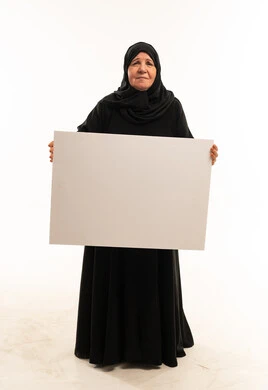 امرأة عربية مسنة تحمل لوحة بيضاء فارغة في الاستوديو