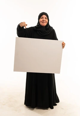 امرأة سعودية مسنة تحمل لوحة إعلانية بيضاء فارغة
