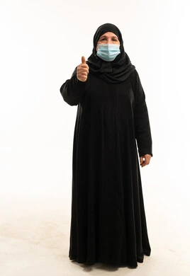 امرأة عربية بالعباءة والكمامة ترفع إبهامها