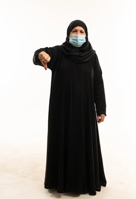 امرأة عربية بالعباءة والكمامة تعطي إشارة الرفض