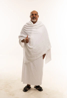 رجل سعودي بملابس الإحرام يرفع إبهامه في استوديو