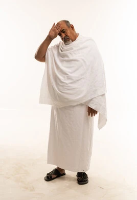 رجل عربي مسن بملابس الإحرام يمسح العرق