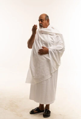 رجل عربي مسن بملابس الإحرام يدعو الله