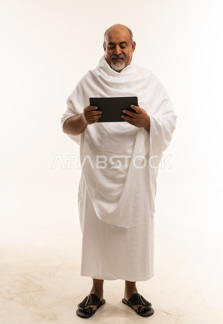 حاج سعودي بملابس الإحرام يستخدم جهاز لوحي