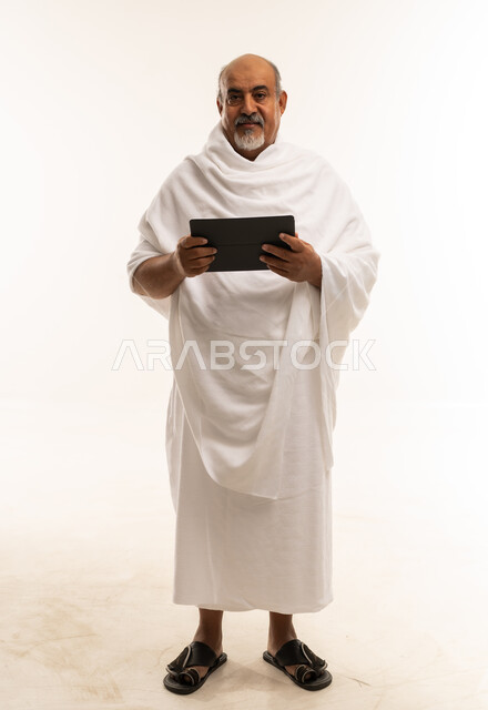 Saudi Pilgrim in Ihram Holding Digital Tablet