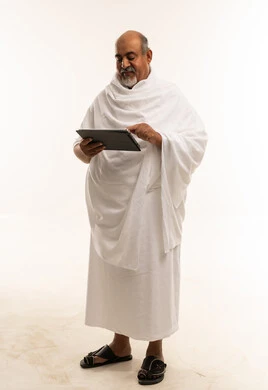 رجل سعودي بملابس الإحرام يستخدم تابلت بخلفية بيضاء