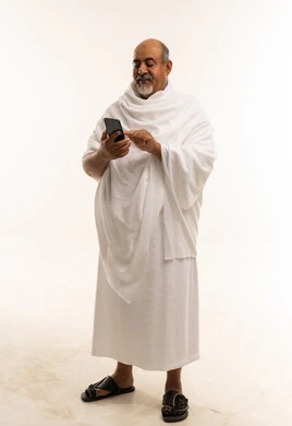 رجل سعودي مسن بملابس الإحرام يستخدم الجوال