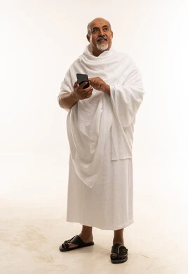 رجل سعودي مسن بملابس الإحرام يستخدم الجوال