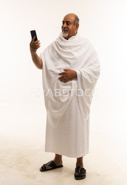 رجل سعودي بملابس الإحرام يستخدم الهاتف الذكي