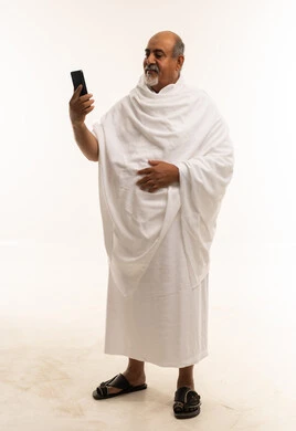 رجل سعودي بملابس الإحرام يستخدم الهاتف الذكي