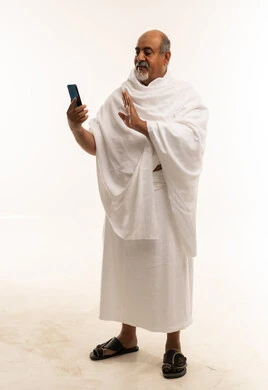 حاج عربي بملابس الإحرام يستخدم الهاتف الذكي