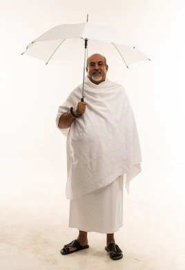 رجل سعودي بملابس الإحرام يحمل مظلة بيضاء