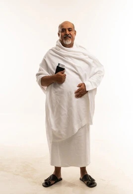 رجل سعودي بملابس الإحرام يحمل جواز سفر بخلفية بيضاء رجل سعودي بملابس الإحرام يحمل جواز سفر بخلفية بيضاء