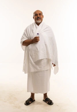 رجل سعودي بملابس الإحرام يحمل زجاجة ماء